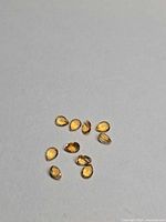 Ten pear-cut golden citrine gemstones arranged on neutral background