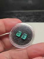 Two octagon-cut emeralds in display case
