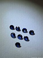 Eight round royal blue sapphires grouped on neutral background