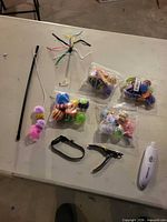 Group shot of all items: teaser wand, bags of assorted cat balls, collar, clippers, treat launcher, Perfect Paw grinder