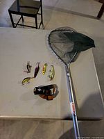Landing net, five lures, headlamp on table
