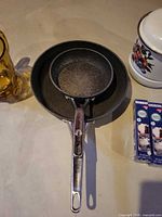 Nested nonstick pans, amber pitcher, portion of cleaner boxes