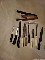 Group shot of nine knives with various handles and three sheaths