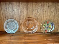Three distinct single plates displayed upright: ribbed starburst, amber floral, floral motif plate