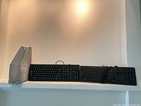 Silver mesh file holder and two keyboards on shelf
