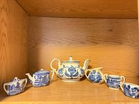 Front view of six blue and white miniature tea pieces on shelf