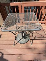 Top view of square mesh patio table showing umbrella hole and metal frame
