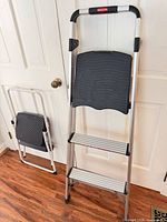 Rubbermaid 3-step ladder and folded single-step stool leaning against door