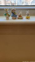Front view of four pastel ceramic bunny figurines on windowsill