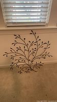 Full view of metal leafy branch wall art leaning against wall