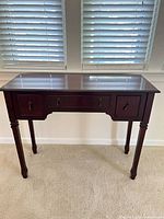 Front view of dark wood console table against wall showing overall form