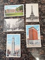 Fronts of five postcards showing Eiffel Tower, campus building, street scene, red brick skyscraper, Met Life clock tower