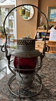Full view of Dietz railroad lantern showing red globe, cage, handle
