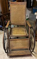 Front view of wheelchair showing cane seat, back, footrest and wheels