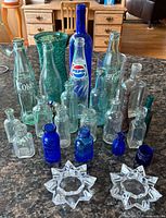 Full lot front view showing variety of bottle sizes, colors and two star candle holders