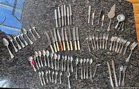 Entire lot laid out showing knives, forks, spoons, serving pieces