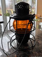 Front view of black metal railroad lantern with amber globe