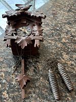 Clock body, chains, and two weights laid flat on surface