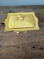 Top view of yellow porcelain covered box with rosebud finial