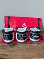 Front view of three Benjamin Moore colour sample jars with red branded bag