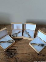 Four boxed silver-plated spreaders on table