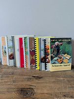 Front view of all ten spiral/comb bound cookbooks upright on table