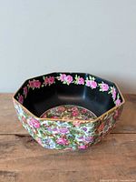 Overall view of octagonal porcelain bowl showing black interior, floral exterior and gold rim