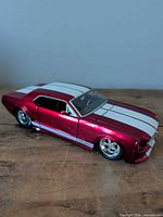 Side/front view of red 1965 Ford Mustang diecast model with white stripes