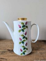 Front view showing floral design, spout, handle, lid with gold trim