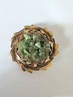 front view showing gold-tone leaf design and green stone chip centre