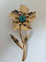 Gold-tone flower brooch with teal rhinestone
