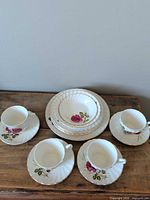 Group view showing cups, saucers, plates and bowl with rose pattern