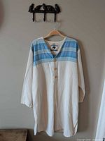 Front view of off-white tunic with blue striped yoke and button front