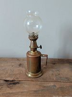 Full view of brass oil lamp with glass globe
