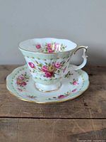 Teacup on saucer displaying floral design and gold trim