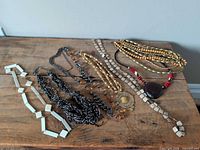 Group shot of seven assorted necklaces laid on wooden surface