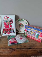 Group shot showing all four items: plate, boxed carolers, sealed mask with ornaments, Santa tray