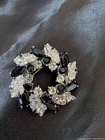 Front view showing full circular brooch design with black cabochons and clear rhinestones