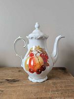 Front view of Winterling porcelain coffee pot showing fruit motif and gold trim