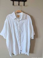 Front view of white embroidered linen short-sleeve shirt on hanger