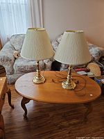 Two brass table lamps with shades on wooden table