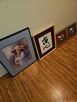 Four framed artworks leaning against wall