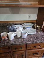 All items grouped: casserole dishes, candle holders, teapot, mugs, glass tumblers