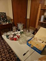 Overall view: coffee urn, punch bowl with cups, mugs, juice jug, snack set plates and cups on table