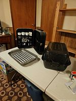 Overall lot showing roaster with lid, broiler pan, open BBQ accessory kit in case