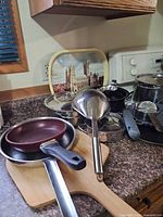 Assorted cookware and wooden pizza peel on counter
