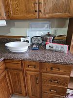 Overall lot showing fondue pot, boxed fondue forks, boxed appetizer plates, casserole dish, and plastic trays