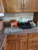Entire assortment on countertop showing grill, pasta maker box, bowls, placemats, tray, mugs