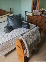Back rest pillow on mattress and pine blanket rack with crocheted blanket