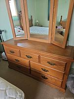 Front view of oak dresser with tri-fold mirror showing seven drawers and brass-tone pulls